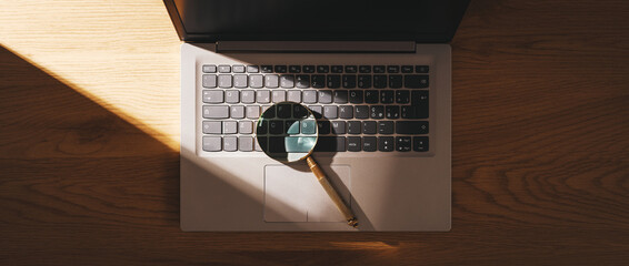 Laptop and magnifying glass on a desk