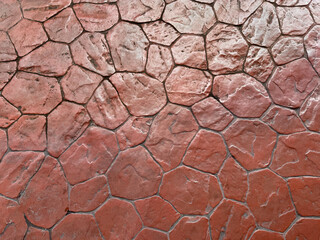 Natural random cut red cobble stones flattened on a floor or wall. Series of natural cobblestones arranged randomly in abstract pattern with grunge and dirt effect. Seamless background for outdoor