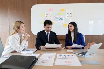 Diverse business team collaborating at a desk, analyzing reports and discussing strategies in a modern office environment.
