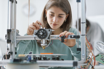Smart female student working with a 3D printer