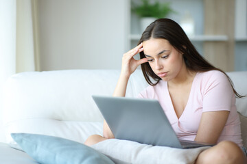 Overwhelmed woman using laptop at home