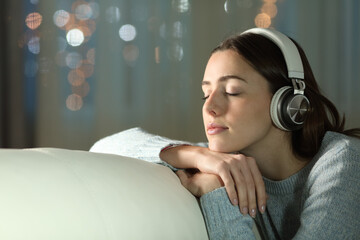 Relaxed woman on a couch listening music in the night
