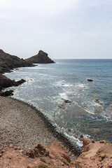 beach of stones and volcanic sand with a calm sea