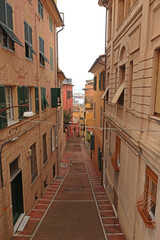 Traditional buildings and steps, pedestrianized narrow streets of old town. Genoa and medieval architecture of Italy. Windows and doors. 