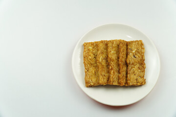Plate of Fried Tempeh Slices, Indonesian Traditional Food Isolated on white background