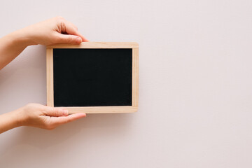 Woman's hand showing chalkboard. Place for writing text on a blackboard. Hands holding a empty black board on white