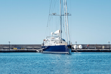 A sailboat rests quietly in turquoise water under a bright sky at a serene marina setting.