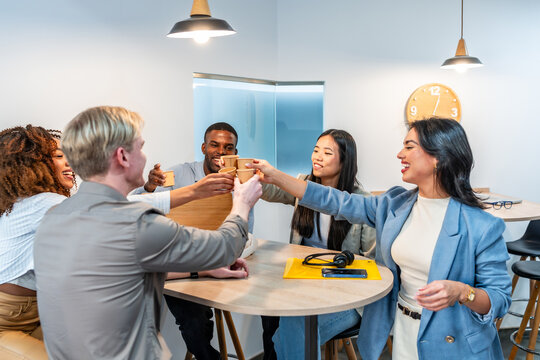 Happy multiethnic business team toasting with coffee in coworking office