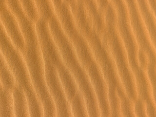 Sand. Texture, surface of sea sand. Natural background. Close-up. Waves of sand. Dunes. Copy space
