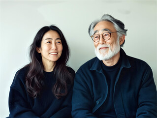 Happy senior Asian couple smiling together against a neutral background, aging gracefully and love in later life
