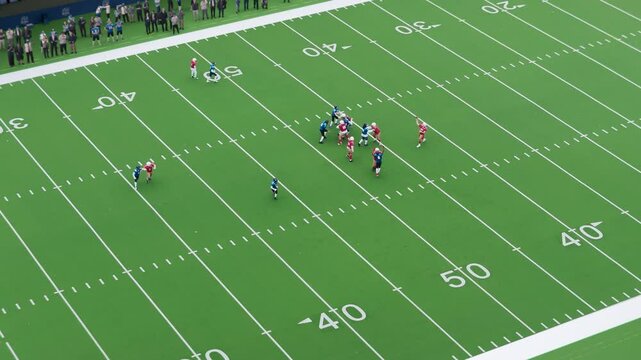 Aerial Drone Footage of Two American Football Teams Standing on the Line of Scrimmage as the Ball is Passed to Start the Game. Footballer Tries to Touchdown. Spectators Cheering From Their Seats