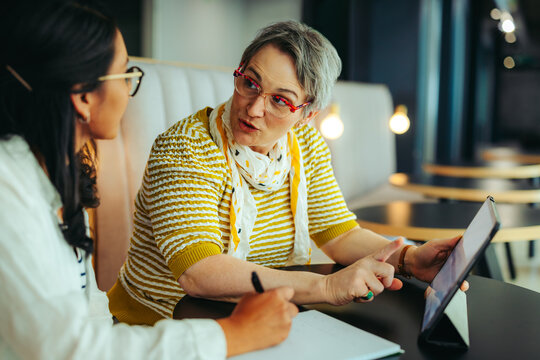 Mature woman giving a private teaching lesson to a young student using a tablet