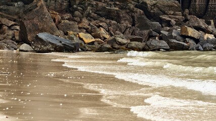 Ocean Waves Gently Washing Onto a Rocky Shoreline with Sandy Beach
