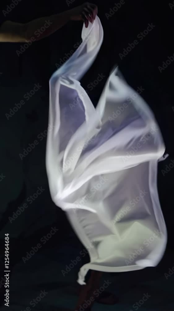 Poster a glowing, ethereal fabric-like structure gently undulating in a dark space, creating a mesmerizing 