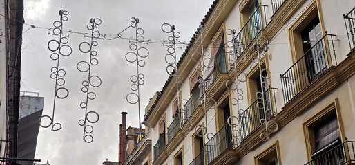 Jerez de la Frontera; festive street decorations with metal rings hang above a traditional building...