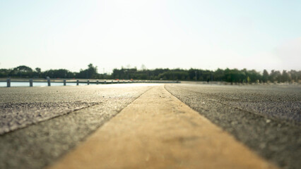 Road with a yellow line down the middle. The road is empty and the sky is clear