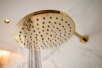 Close up of a gold color shower head attached to a wall
