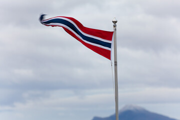 Norwegische Flagge am Fahnenmast mit Wolken und Wind.