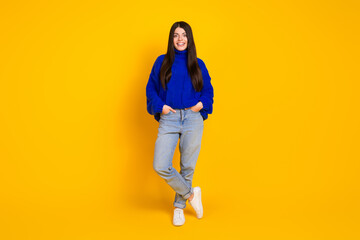 Fototapeta premium Young woman in blue sweater posing confidently against bright yellow background