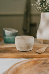 A white bowl sits on a wooden cutting board. The bowl is empty and the cutting board is made of wood