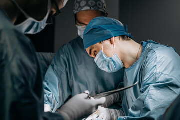 A team of professional surgeons performs surgery in a modern hospital. Concept skills working using...
