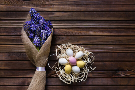 colorful easter eggs in a nest on a wooden background. spring flowers