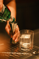 Bartender hand pouring alcohol to Jigger. Bartending and mixology