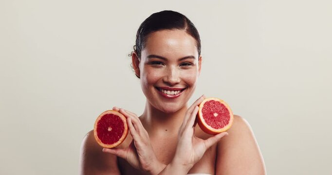 Girl, beauty and happy with grapefruit in studio, face or choice for diet with skincare by white background. Woman, person and model with nutrition, smile or benefits for cosmetic results in Colombia