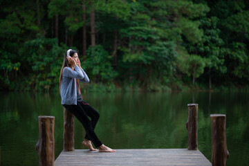 Woman listens to music via Bluetooth headphones, enjoying the peaceful lakeside view