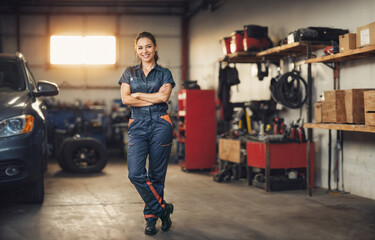 Eine junge h&uuml;bsche br&uuml;nette l&auml;chelnde KFZ-Mechanikerin in einer Autowerkstatt