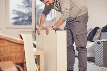 Fototapeta premium Man working and assembling furniture in a new apartment.