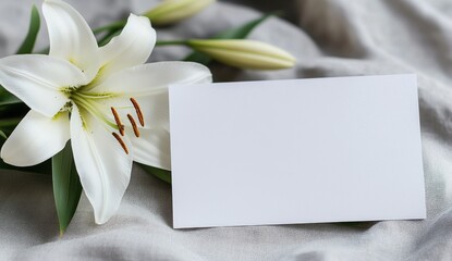 White lily flower and blank card on gray fabric.
