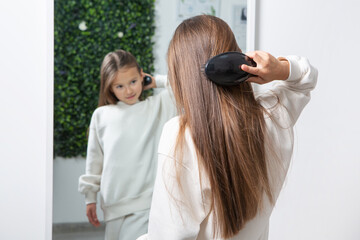 Fototapeta premium Happy Kid Getting a New Hairstyle in a Modern Salon Little Girl Sitting in a Salon Chair During Haircut 
