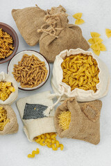 Pasta. Various kinds of uncooked pasta and noodles over light stone background. Traditional Italian