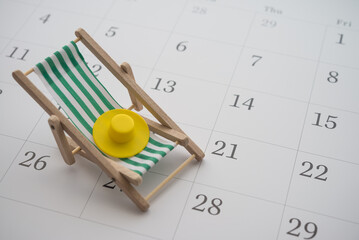 Green beach chair and hat on white blank calendar background copy space. Annual leave travel period...