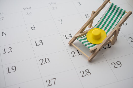 Green beach chair and hat on white blank calendar background copy space. Annual leave travel period for relaxation concept. Period of paid time off (PTO) granted to employees by their employer.