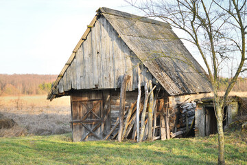 Old wooden barn stands in a serene rural landscape during daylight