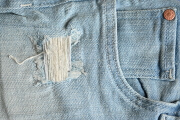 torn light grey denim surface, denim fringe , hole macro texture of blue denim, torn blue denim texture as background photo close up from above	
