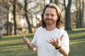 Open and welcoming man in park. Expressive, friendly, and inviting.