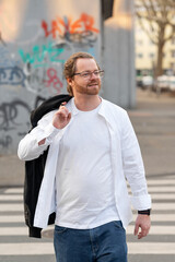 Fototapeta premium Confident man crossing the street in an urban setting. Style and purpose.