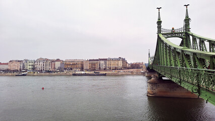 Southern end riverside of the Pest City Centre with the Liberty Bridge on the right that connects Buda and Pest. View of Buda along the Danube River shore at a winter sunset, Budapest, Hungary, Europe