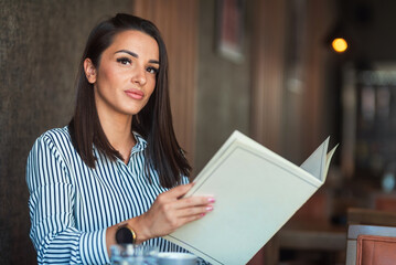 Obraz premium Young businesswoman reading menu in restaurant