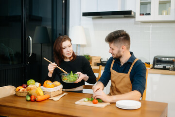 Discover a joyful couple preparing fresh vegetables, embracing healthy eating and teamwork in a...