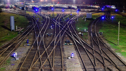 railroad, tracks and switches at a freight railway station at night, freight cars and traffic...