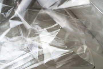 Crumpled clear plastic background, abstract glossy broken surface texture with creases