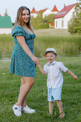 Happy mother and son dancing on the grass, laughing, tickle each other, spending time together in...