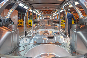 Passenger car parts ready for assembly on a conveyor line.