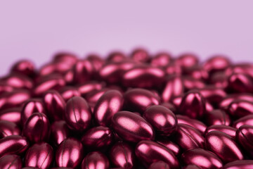 red softgels capsules of vitamins on pink background