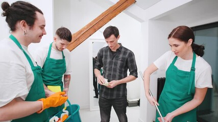 The client pays money to the team of cleaners from the cleaning service for a job well done