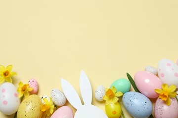 Happy Easter. Colorful eggs, yellow flowers and Easter bunny ears on a pastel color background,...
